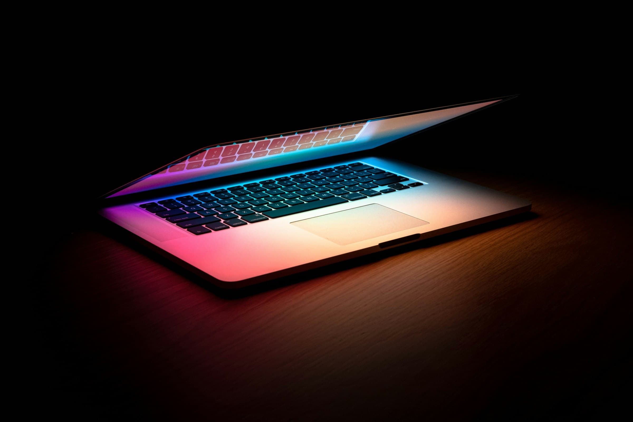 A MacBook glowing softly on a desk at night